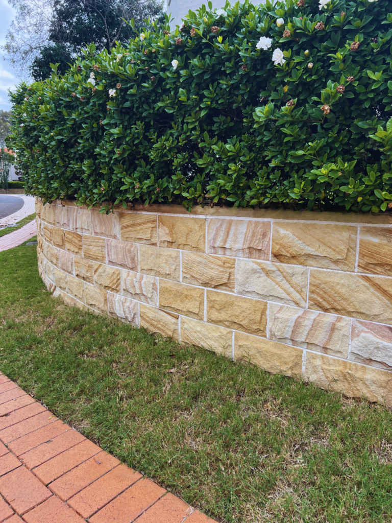 Immaculately restored sandstone retaining wall post-cleaning, with its natural color and texture revived. The previously visible black mould and dirt have been meticulously removed, showcasing the wall's enhanced appearance and the effectiveness of the cleaning process.